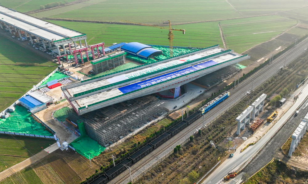跨京沪铁路转体桥上部结构采用预应力混凝土T构，跨径组合为（68+68）米，下部结构主墩采用“V”型空心墩设计，整幅桥梁全宽38.33米，转体重量高达25680吨，主承台深基坑开挖处临近繁忙干线京沪铁路，距路基坡脚线最近处仅有15米，临近铁路基坑开挖深度10余米，施工过程复杂、精度要求高。图为转体桥转体中。