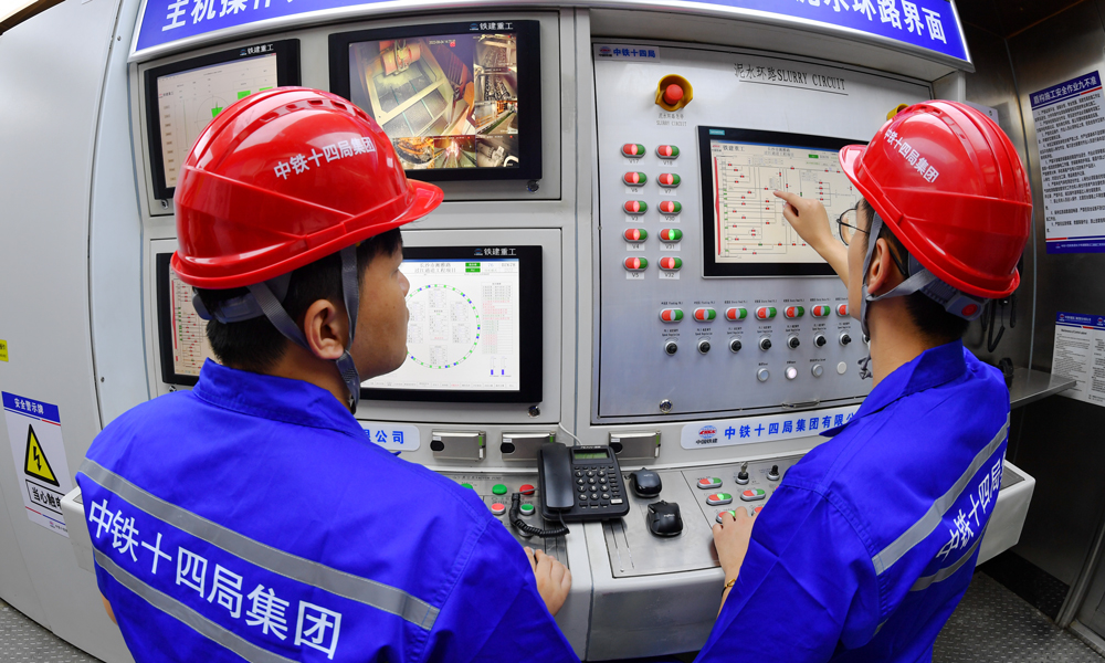 湘雅路过江通道工程总投资53.278亿元，隧道全长4180米，其中过江段1429米。采用一台开挖直径15.01米的泥水平衡盾构机掘进，设计为双管双向六车道，行车时速50公里。据介绍，量身打造的“星盛号”盾构机是目前国内最先进的智能掘进设备之一。项目团队攻克了施工地质条件复杂、大坡度小曲线始发等施工难题，8次组织专业潜水员进仓换刀，累计进仓1300余仓，更换刀具800余把，创造了盾构施工岩层掘进月均180米、最高月进尺280米的施工记录，为同类型水下岩层大直径盾构隧道施工积累了宝贵经验。图为建设者正在操作盾构机。